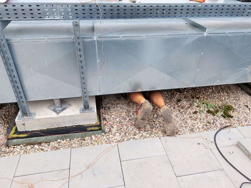 Nur Beine von Techniker unter Aufbaut zu sehen, bei einer Flachdach Leckortung von ILD Deutschland.